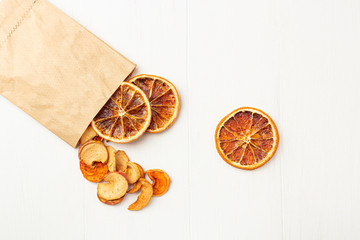 Organic homemade dry fruit chips in a paper eco pack on a white background. Healthy vegan snack of apples and orange. The concept of proper nutrition, organic and vegetarian food.