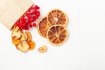 Organic homemade dry fruit chips in a paper eco pack on a white background. Healthy vegan snack of apples and orange. The concept of proper nutrition, organic and vegetarian food. T