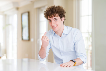 Young business man with curly read head Beckoning come here gesture with hand inviting welcoming happy and smiling