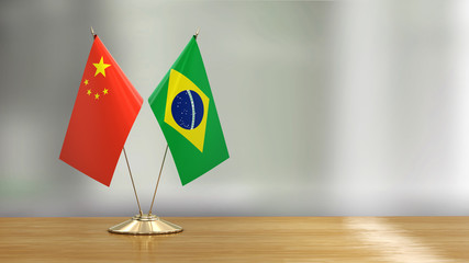Chinese and Brazil flag pair on a desk over defocused background 