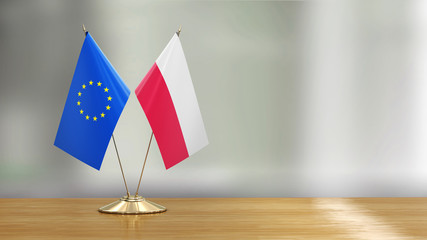 European Union and Polish flag pair on a desk over defocused background 