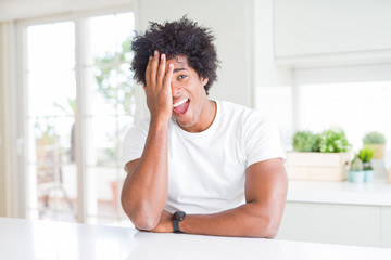 Young african american man wearing casual white t-shirt sitting at home covering one eye with hand, confident smile on face and surprise emotion.