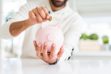 Man putting a coin inside of piggy bank saving for investment