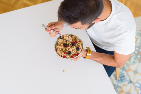 Above angle of handsome man eating healthy cereals for breakfast in the morning