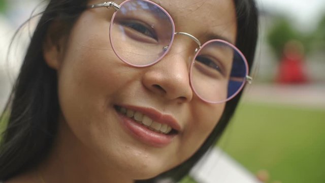 Closeup portrait of cute Thai Girl in glasses outdoors. Slow motion