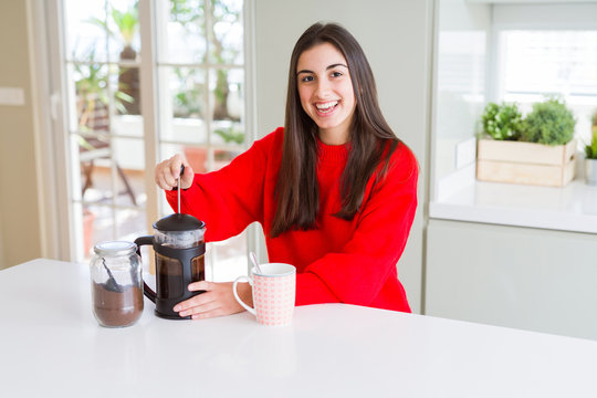 Young beautiful woman making morning coffee smiling, preparing a cup of latte for breakfast