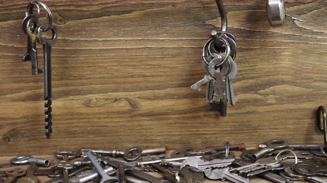 Metal keys hang on the hooks and the keys situated on a wooden background
