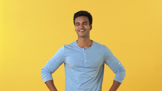 Young smiling Indian man pointing and giving thumbs up empowering you on yellow studio background