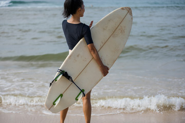 Surfer woman with surfboard on the beach
