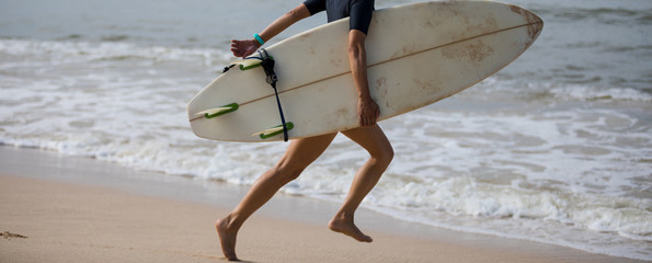 Surfer woman running with surfboard on the beach