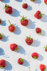 Strawberry on a white background, pattern with shadows. Top view layout in bright light.