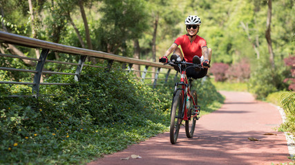 Naklejka premium Woman cyclist riding mountain bike outdoors,have fun with legs on handlebar