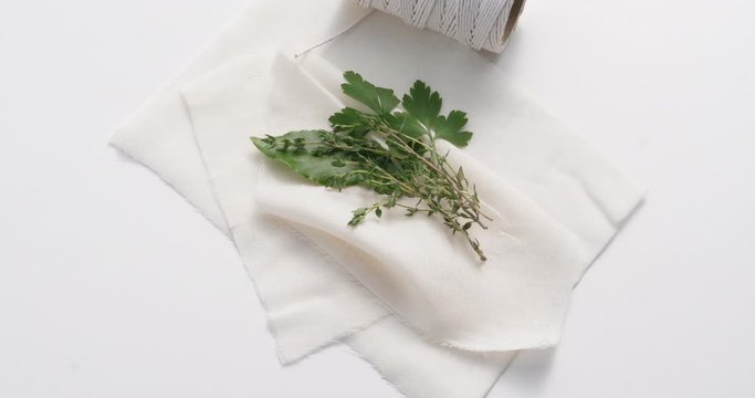 A slight breeze on traditional ingredients for a bouquet garni herb spice mix including a bay leaf, parsely and thyme ready to be wrapped in cheese cloth.