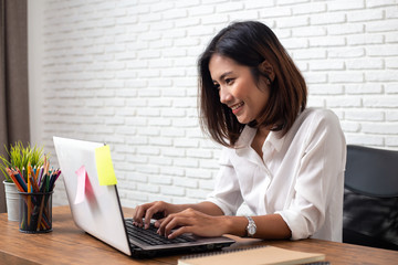 young asian woman working  laptop computer on wood desk in Home office
