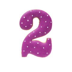 Sugar cookie or gingerbread in form of Arabic numeral two, covered with purple royal icing with white polka dots. Iisolated objects on a white background.