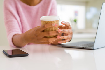 Close up of young woman drinking a coffee while working using laptop