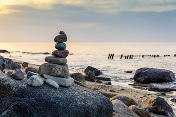 pyramid of small smooth stones by the sea against the sunset sky