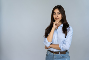 Thoughtful serious doubtful young indian adult woman standing isolated on grey studio background with copy space. Pondering lady student professional thinking of new idea looking at camera, portrait