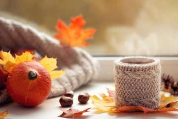 Mug of hot coffee on the window. Home cozy morning and thanksgiving day concepts. pumpkin and autumn leaves