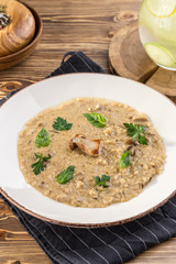 Risotto with porcini mushroom with basil and parsley serving size on wooden table