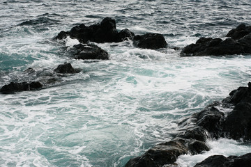Volcanic stones on ocean shore, cold clean water, waves, Madeira island, Portugal