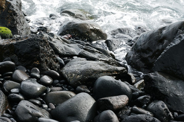 Volcanic stones on ocean shore, cold clean water, waves, Madeira island, Portugal