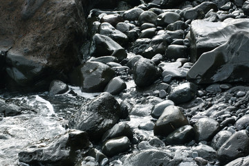 Volcanic stones on ocean shore, cold clean water, waves, Madeira island, Portugal