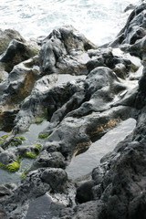 Fototapeta na wymiar Volcanic stones on ocean shore, cold clean water, waves, Madeira island, Portugal