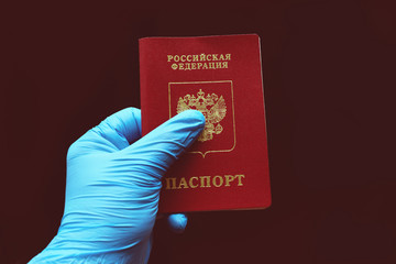 Russian passport in a hand in a blue glove. The inscription in Russian: Russian Federation,...