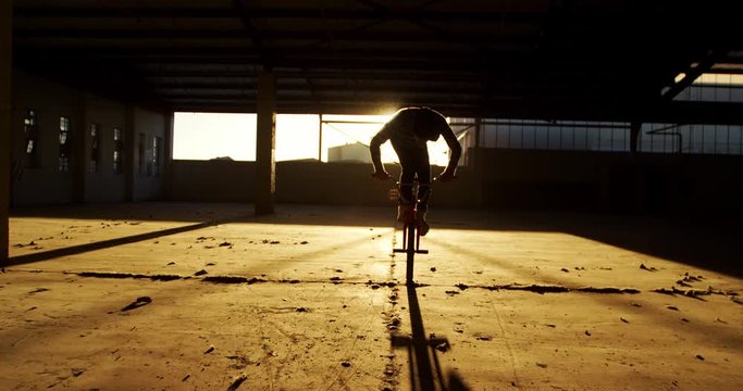 BMX rider in an empty warehouse