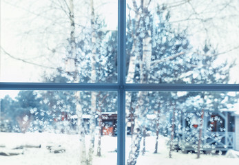 View of the courtyard in winter through a frozen window in snowflakes and hoarfrost. Christmas and winter time concept