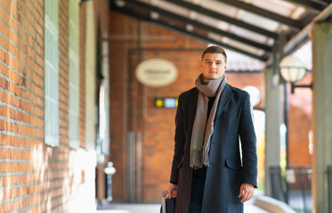 Young man in overcoat and scarf approaching