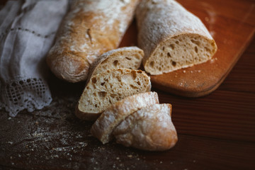 Chiabatta homemade bread. Fresh baked bread on a kitchen board and wooden background. White bread and chopped slices.