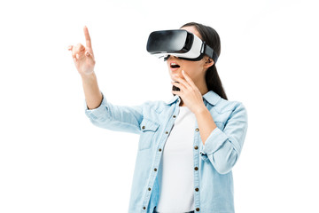 shocked woman in denim shirt with virtual reality headset pointing with finger isolated on white