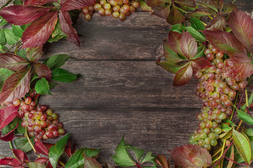 Beautiful wreath frame with grapes, leaves and vine on wooden boards. Fall concept. Flat lay style.