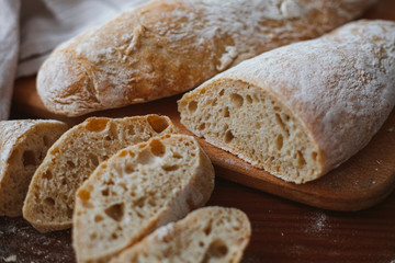 Chiabatta homemade bread. Fresh baked bread on a kitchen board and wooden background. White bread and chopped slices.
