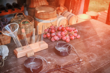 Professional winemaking, table with grapes and flasks for sampling. Barrels for wine, bottles and grapes in baskets.