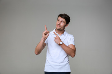 Image of handsome brunette man smiling and pointing fingers upward