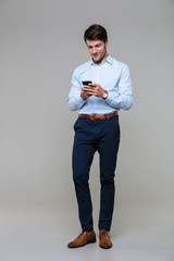 Full length portrait of happy young businessman holding smartphone