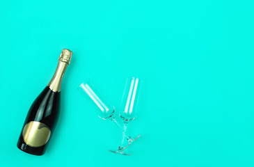 Champagne bottle and two glasses on trendy mint background with place for text. Holiday concept. Mockup for your design. Flat lay style.