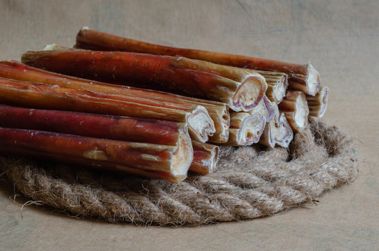 12 pieces of bully sticks of regular size on a natural hemp rope. Close-up. Soft focus. Landscape orientation. Eye level shooting.