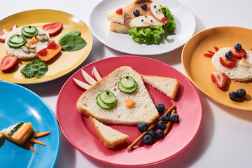 plates with fancy animals made of food for childrens breakfast on white background