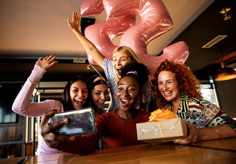 Group of girls surprise their girlfriend with a birthday party at a coffee shop and making selfie.
