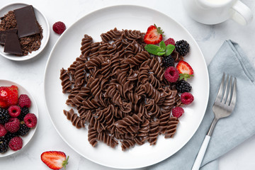 Chocolate fusilli pasta with fresh berry on white plate