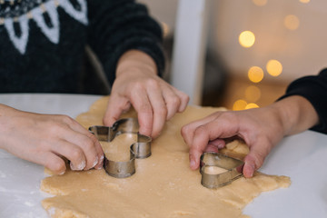 Fototapeta na wymiar Young kids baking Christmas gingerbread cookies in house kitchen on winter day. Close-up child's hands preparing cookies using cookie cutters. Cooking with children for XMas at home. Selective focus
