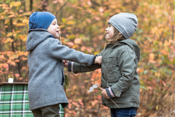 Children playing in autumn forest full of yellow leaves with vintage suitcase. Brother and sister friends forever.