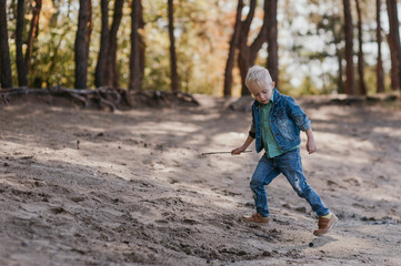 Emotional portrait of a happy and cheerful little boy, running after a friend laughing while playing on a walk in the park. Happy childhood. Summertime. Summer vacation. Positive emotions and energy