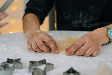 Young kids baking Christmas gingerbread cookies in house kitchen on winter day. Close-up child's hands preparing cookies using cookie cutters. Cooking with children for XMas at home. Selective focus