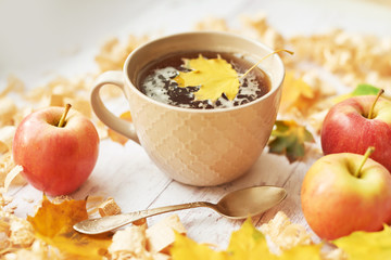 Cup with tea. Autumn background with yellow maple leaves and apples. Frame of fall harvest on aged wood with copy space. Mockup for seasonal offers and holiday post card. Thanksgiving Day. Halloween 