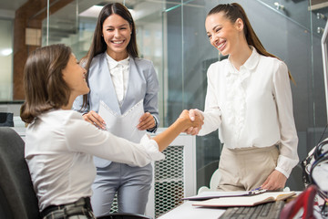 Young business women shaking hands in office